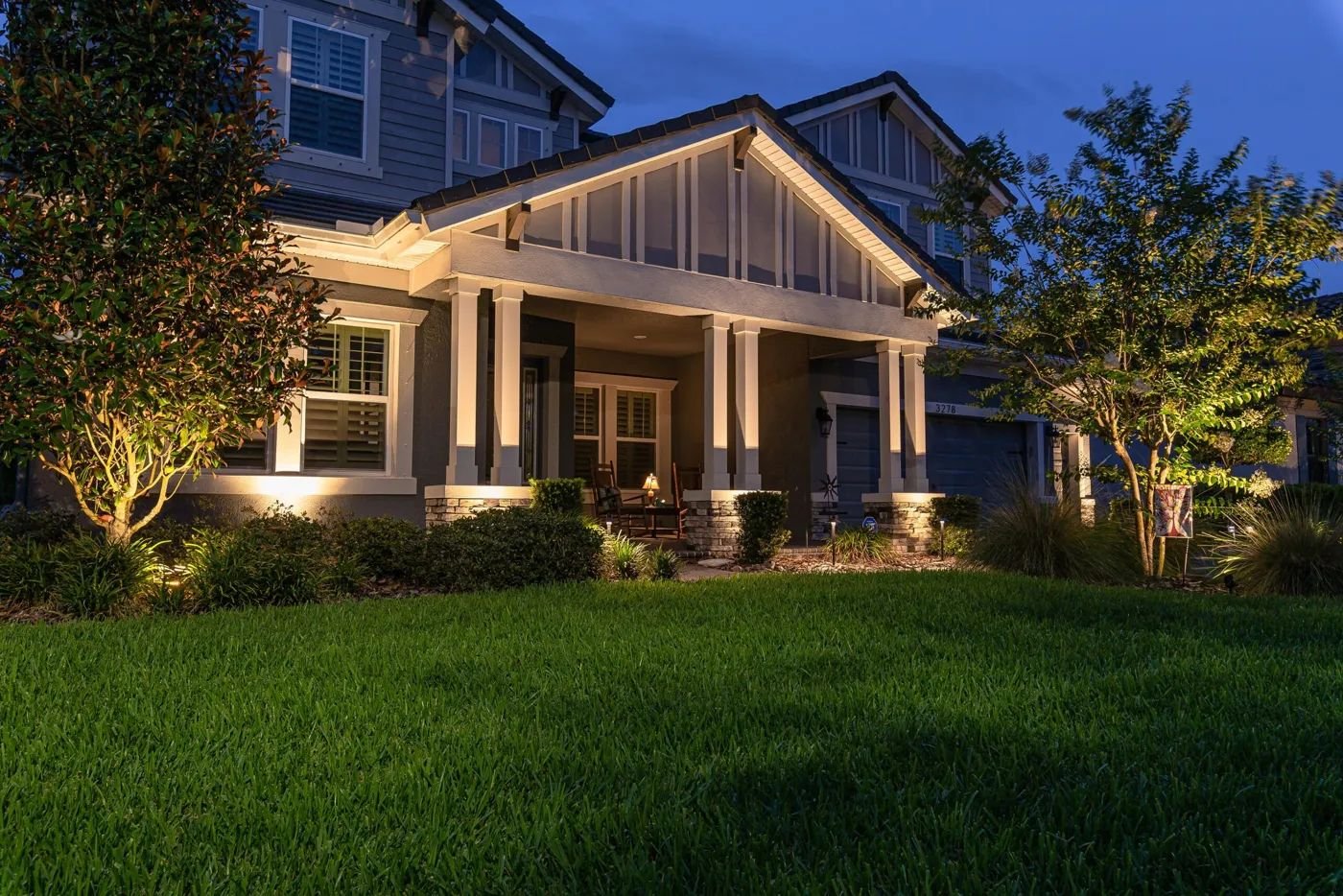 Front of a craftsman home with a covered porch, lit warmly at dusk