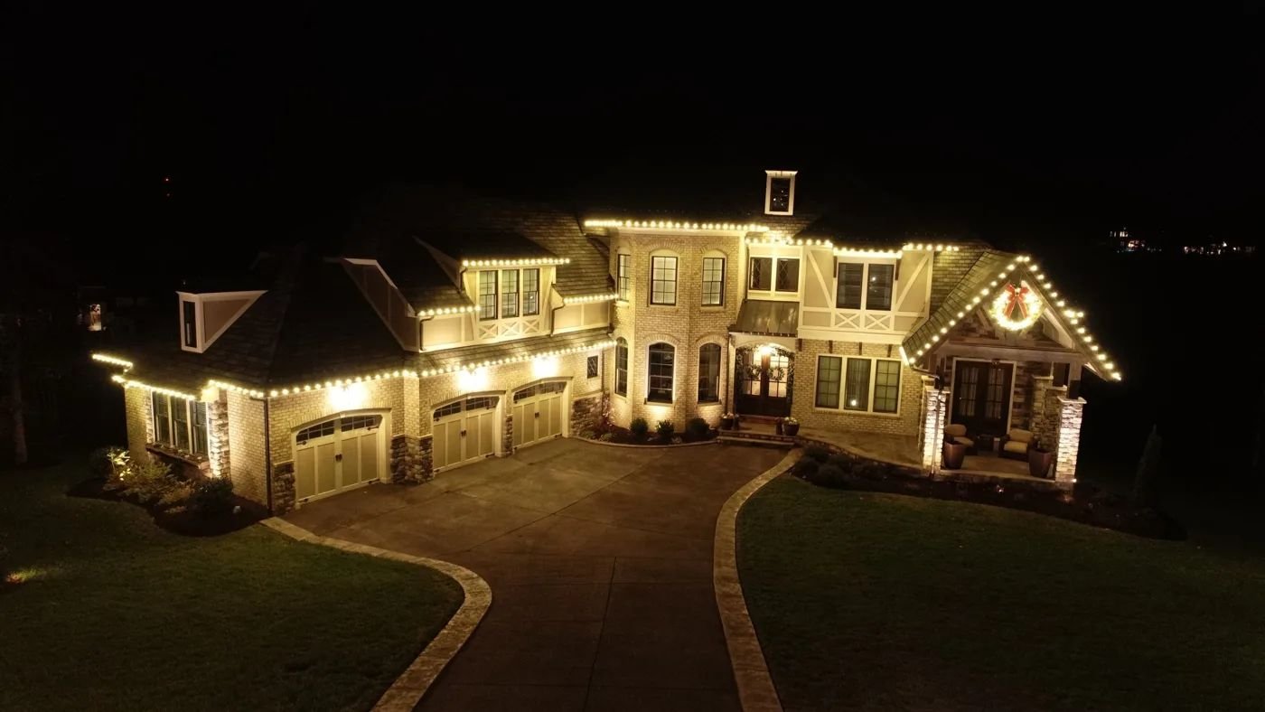 Large brick home at night with lights along every roofline
